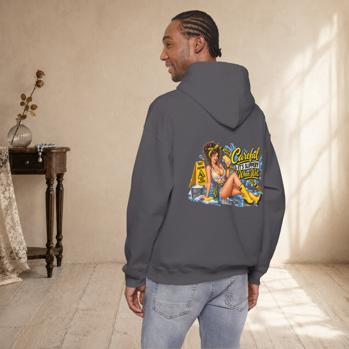Male model wearing a charcoal unisex hoodie at a three-quarter angle showing the vintage pin-up back design