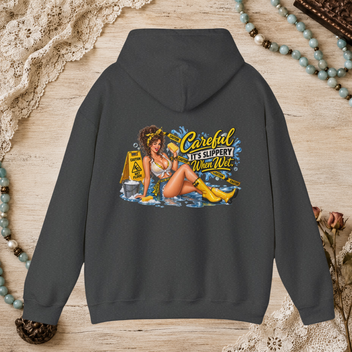 Back of a dark heather unisex hoodie featuring the Careful It’s Slippery When Wet vintage pin-up design