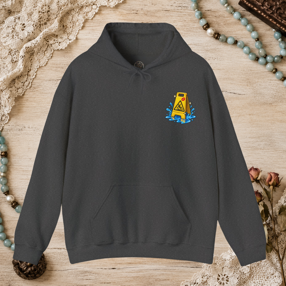 Front of a dark heather unisex hoodie with a small yellow wet-floor caution graphic on the left chest