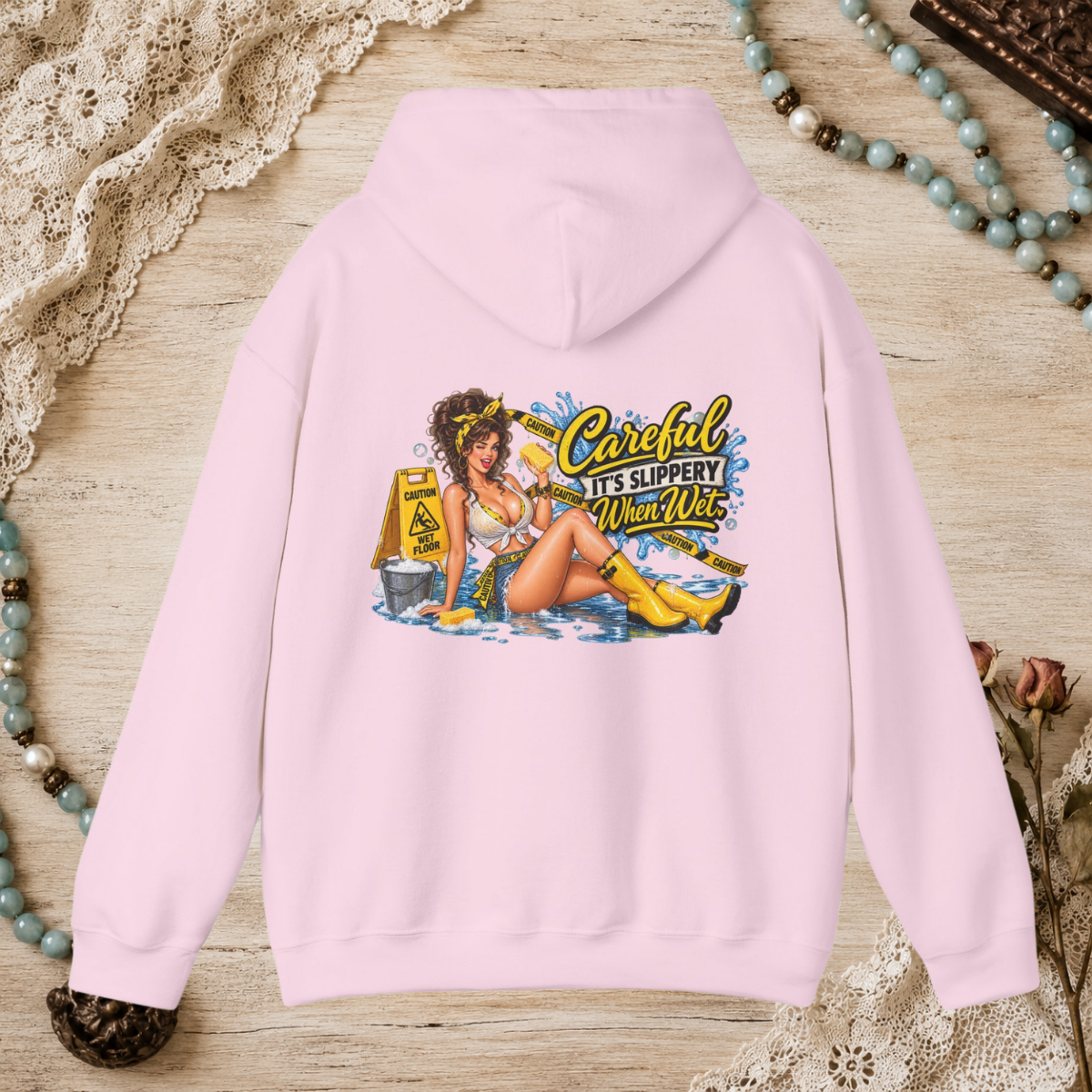 Back of a light pink unisex hoodie featuring the Careful It’s Slippery When Wet vintage pin-up design