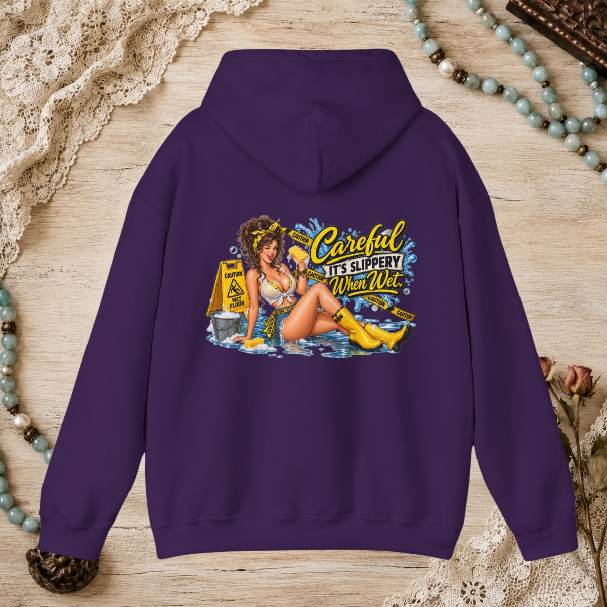 Back of a purple unisex hoodie featuring the Careful It’s Slippery When Wet vintage pin-up design