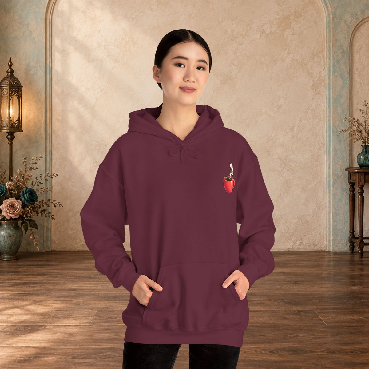Female model wearing a maroon hoodie with a small red coffee cup and heart-steam design on the front