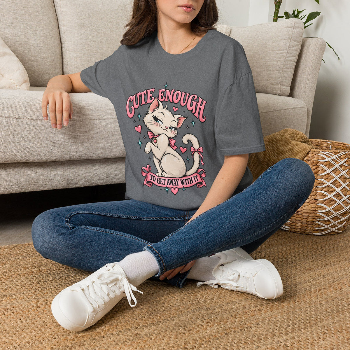Woman seated on a sofa wearing a Graphite Heather Cute Enough to Get Away With It unisex graphic T-shirt