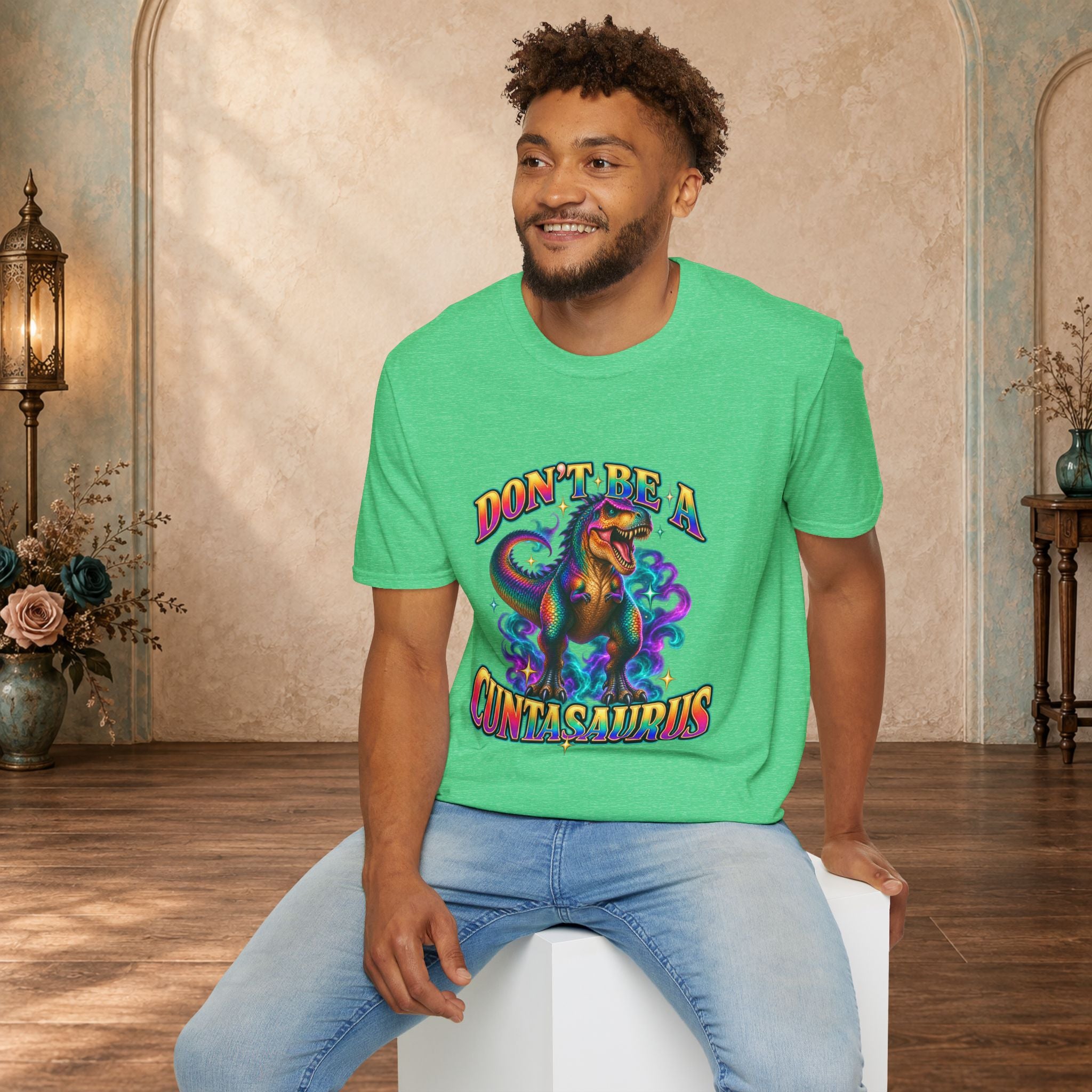 Man wearing a heather Irish green Don’t Be a Cuntasaurus dinosaur graphic tee
