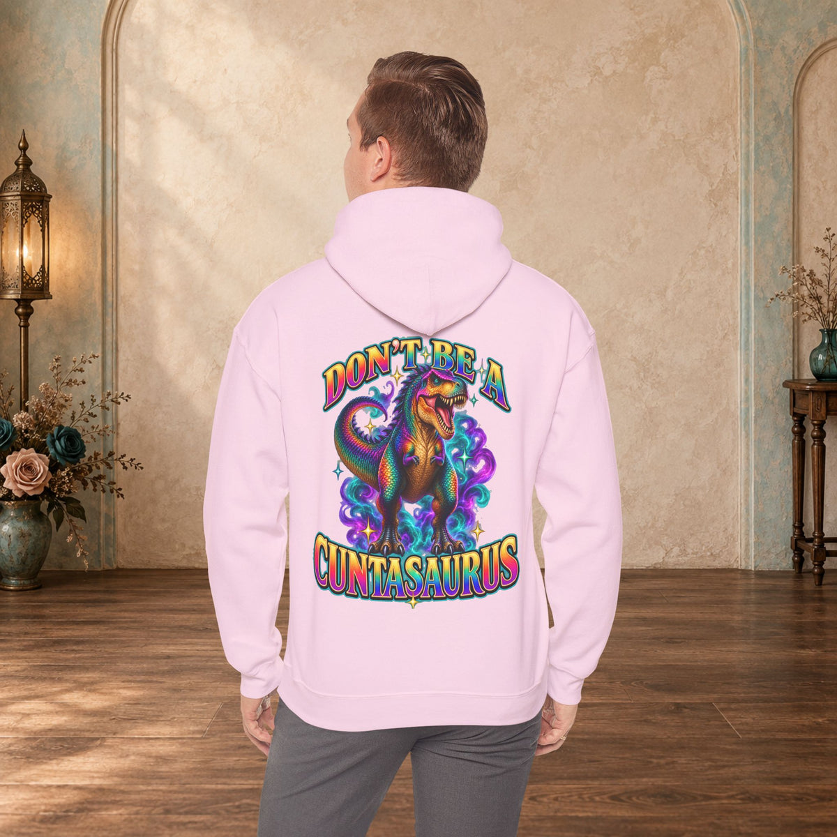 Man wearing a light pink Don’t Be a Cuntasaurus funny dinosaur hoodie shown from the back