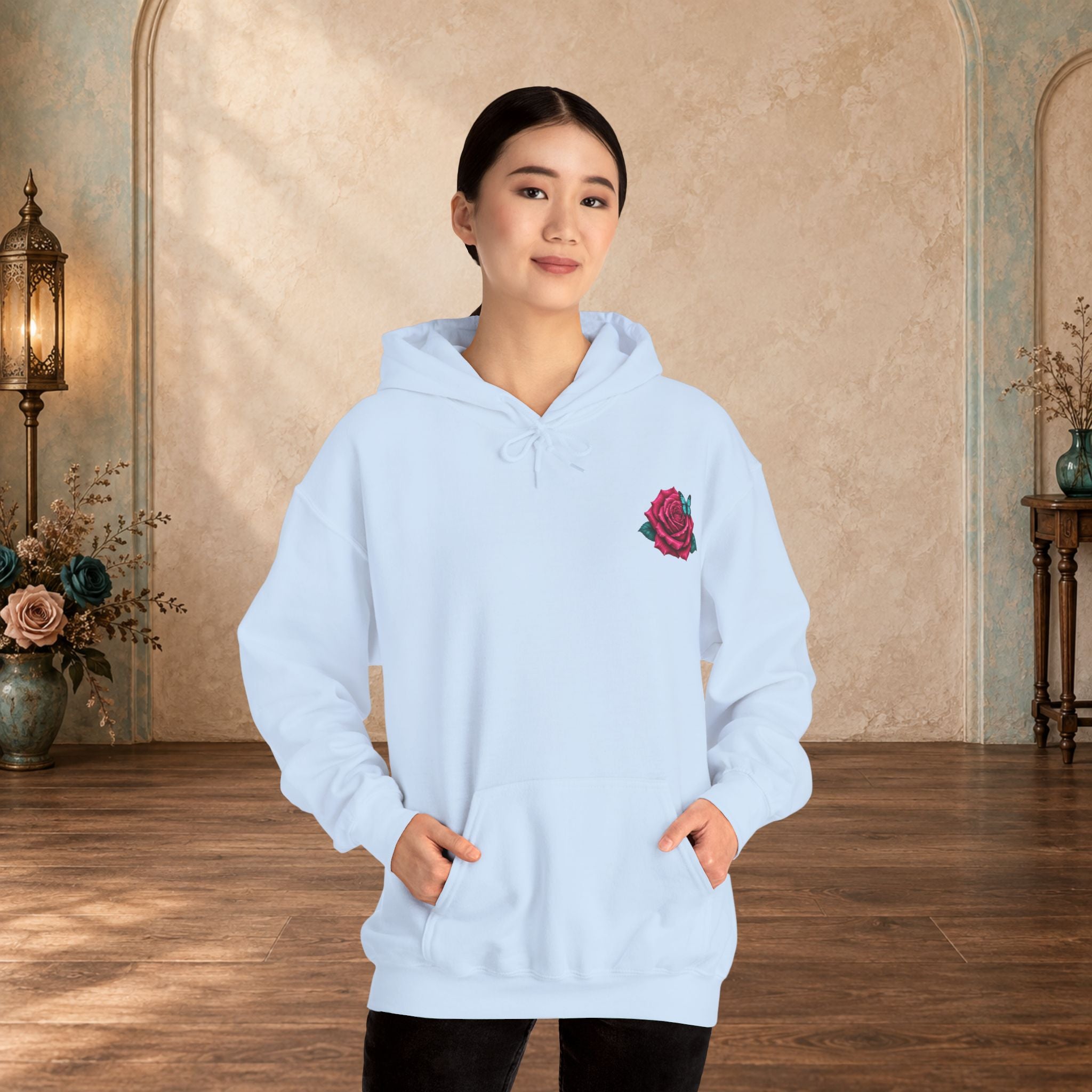 Female model wearing a light blue hoodie with mauve rose and turquoise butterfly chest design