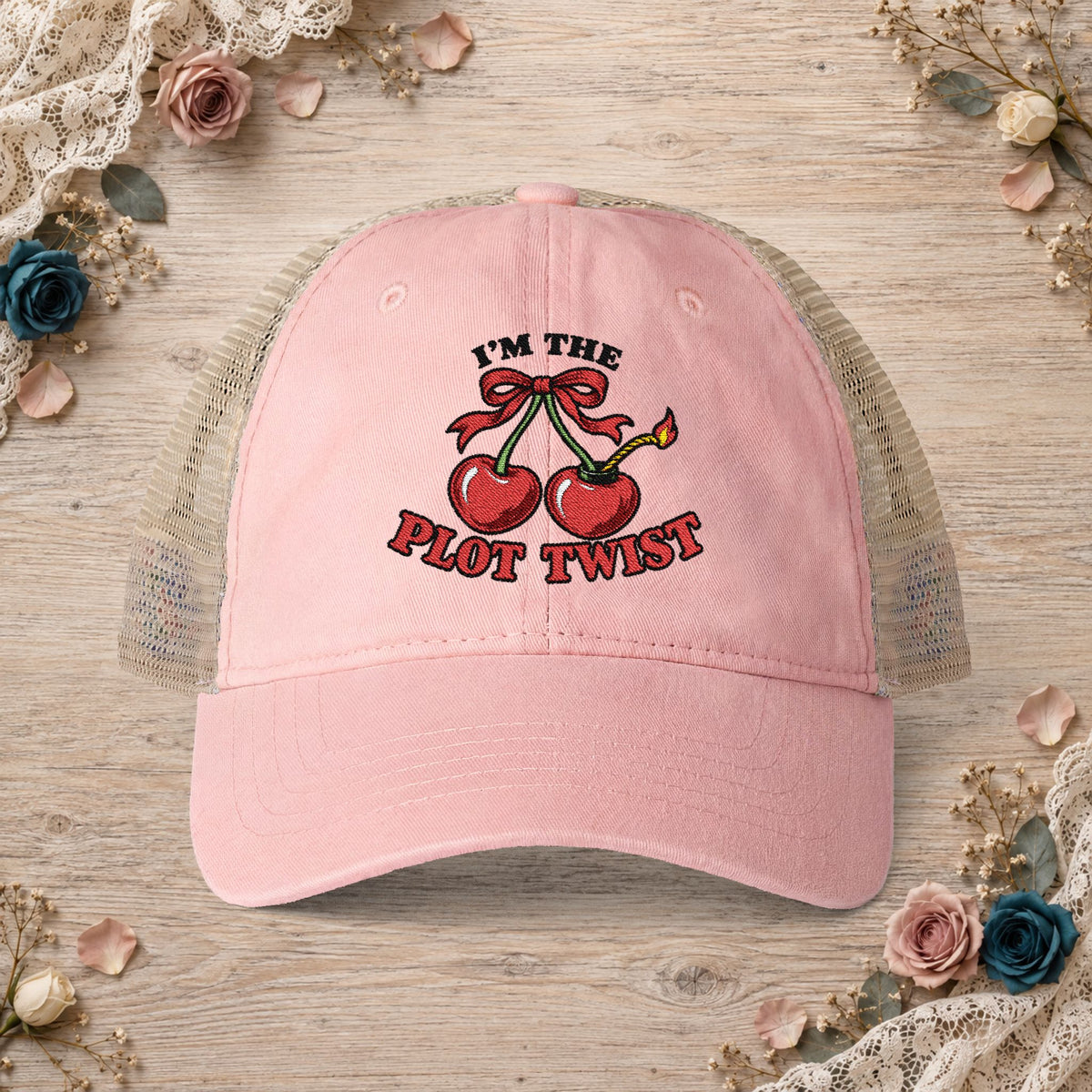 Dusty pink women’s mesh-back hat with an embroidered I’m the Plot Twist cherry bomb design.