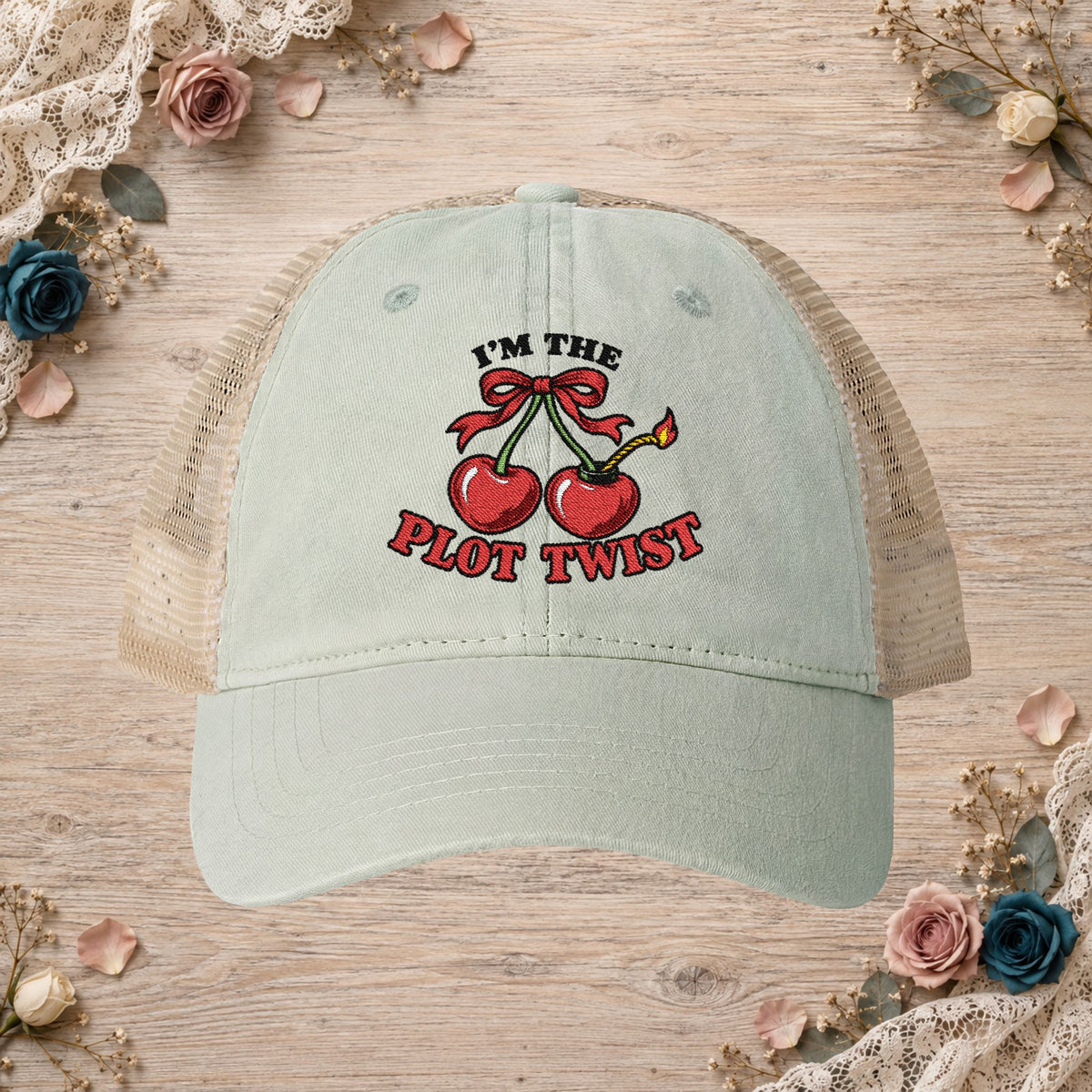 Sage women’s mesh-back hat with an embroidered I’m the Plot Twist cherry bomb design.