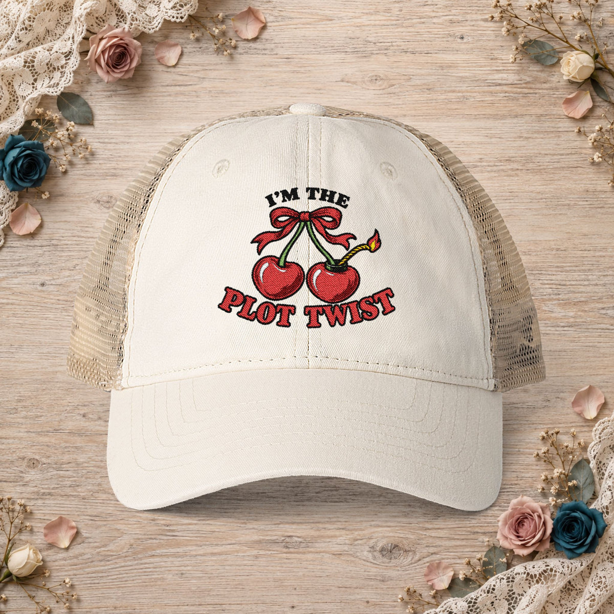 Vanilla women’s mesh-back hat with an embroidered I’m the Plot Twist cherry bomb design.